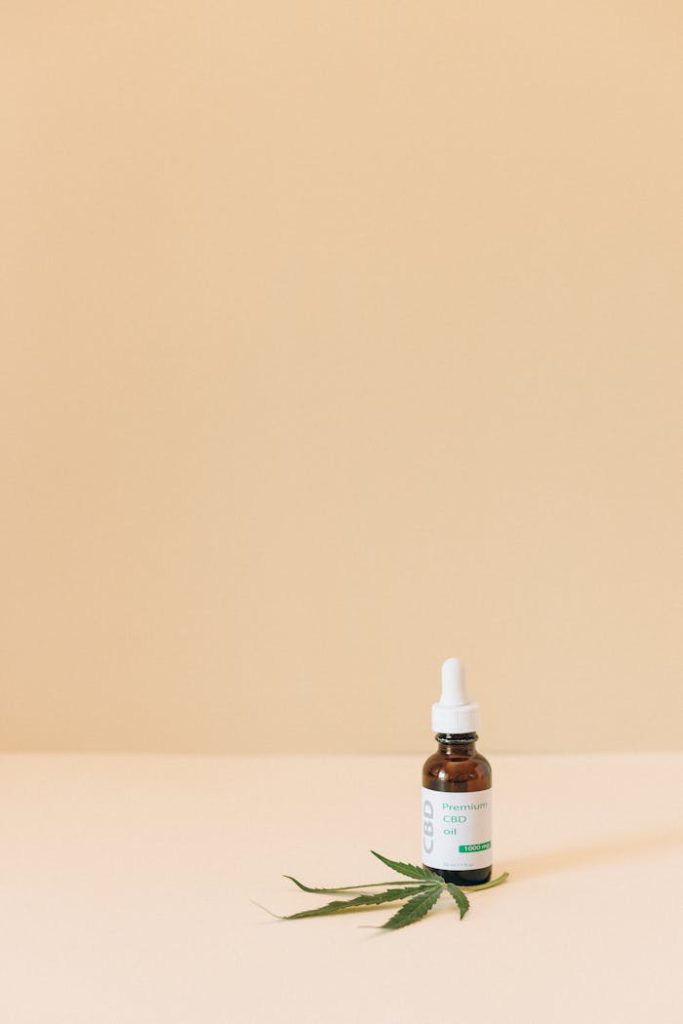Minimalist image of a CBD oil bottle with a cannabis leaf on beige background.